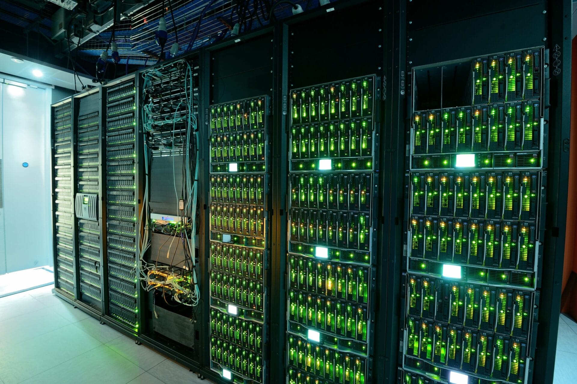 Picture of Data servers, they are lit up green and there is 6 large servers in the image.