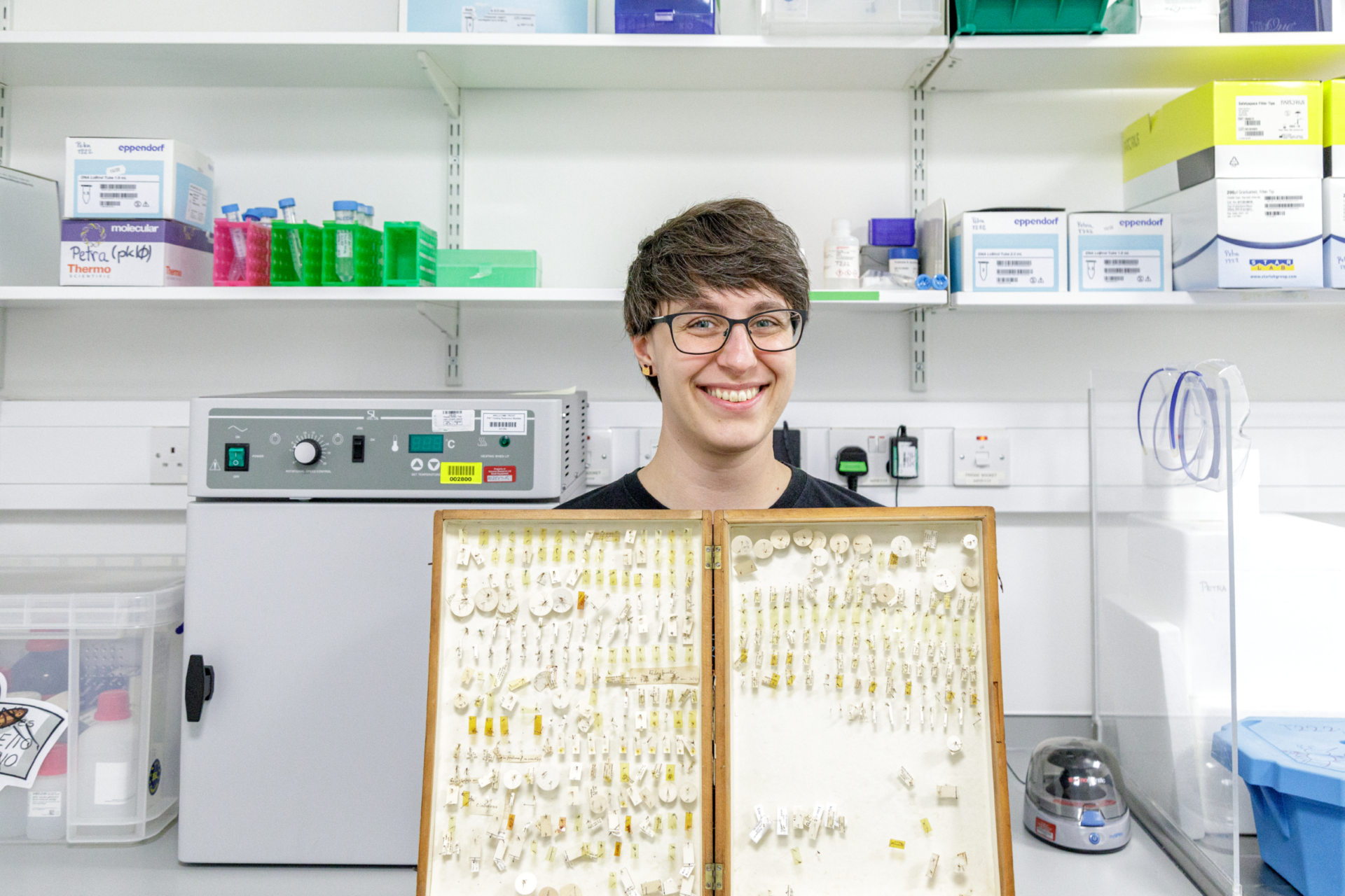 Petra is standing in a lab proudly showing one of her science samples from a project she is working on.