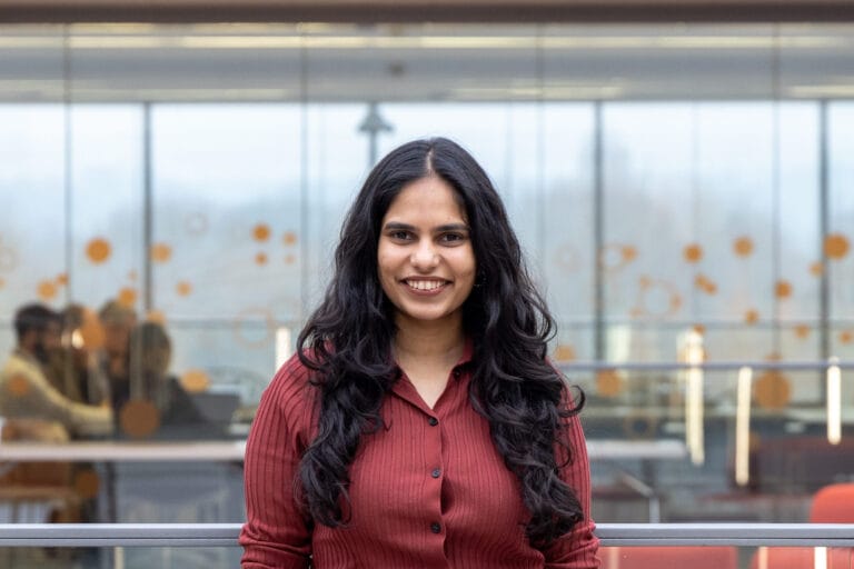 Image of Disha in the foyer of a building, smiling at camera.